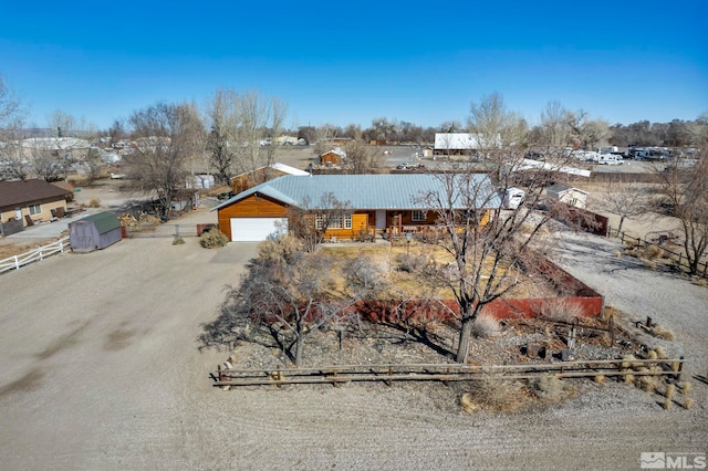 chalet / cabin with metal roof, fence, dirt driveway, and a detached garage