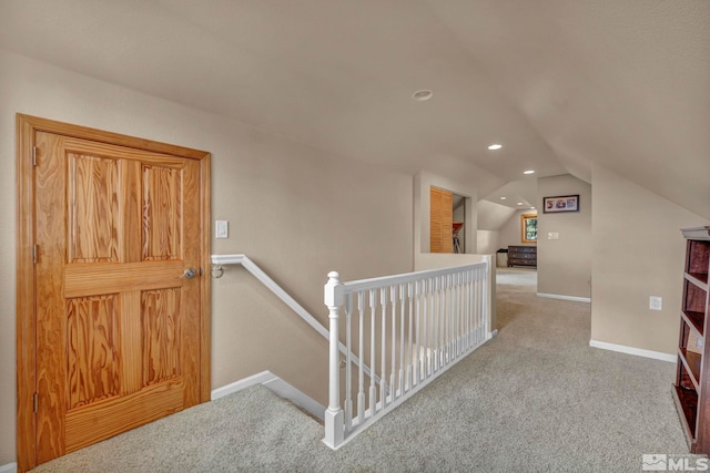 corridor featuring lofted ceiling, carpet, an upstairs landing, and baseboards