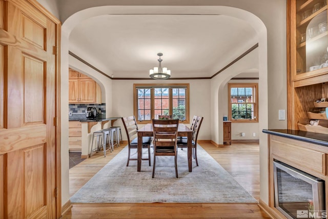 dining room featuring light wood finished floors, plenty of natural light, arched walkways, and a notable chandelier