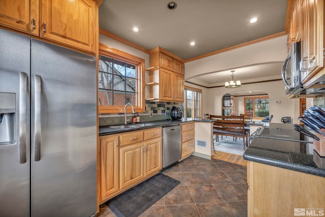 kitchen featuring decorative backsplash, appliances with stainless steel finishes, a sink, crown molding, and a wealth of natural light