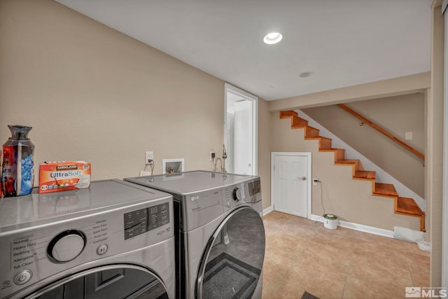 clothes washing area with washer and dryer, laundry area, baseboards, and light tile patterned floors