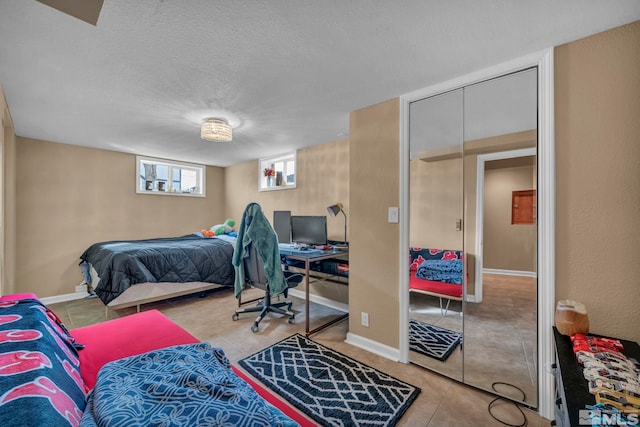 bedroom featuring tile patterned flooring, baseboards, and a textured ceiling