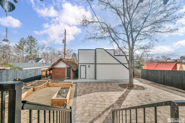 rear view of property with a fenced backyard, a patio area, and a vegetable garden