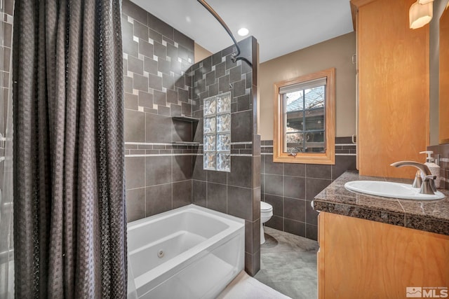 full bathroom featuring a wainscoted wall, tile walls, toilet, vanity, and shower / tub combination