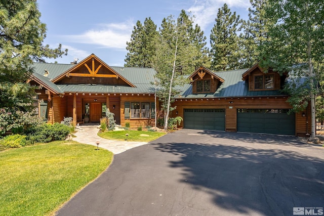 view of front of property featuring a garage, driveway, a front lawn, and metal roof