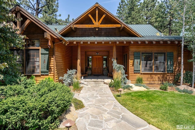 log cabin with a front yard, a standing seam roof, covered porch, and metal roof