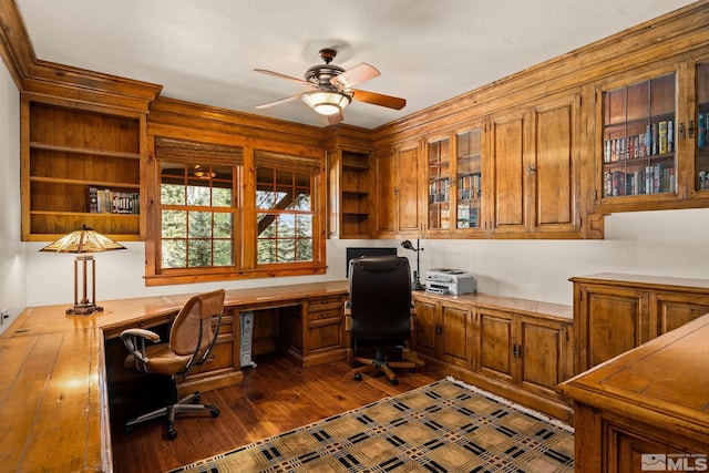 home office with dark wood finished floors, built in desk, and ceiling fan