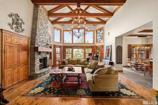 living room with a stone fireplace, light wood-style flooring, beam ceiling, and an inviting chandelier