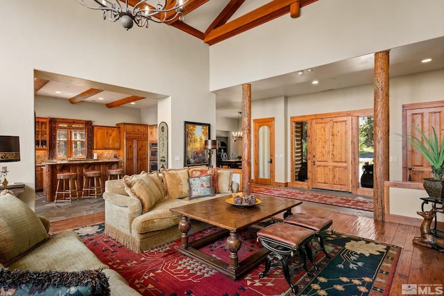 living area featuring high vaulted ceiling, wood-type flooring, beamed ceiling, and an inviting chandelier