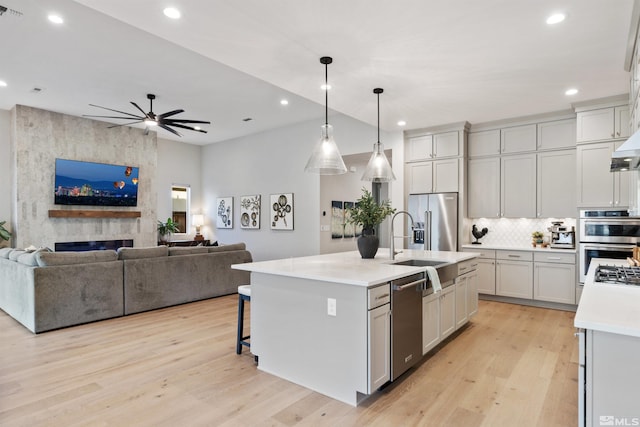 kitchen with appliances with stainless steel finishes, open floor plan, light countertops, and light wood-style floors