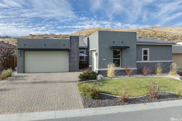 view of front of home with a mountain view, a garage, stone siding, decorative driveway, and stucco siding