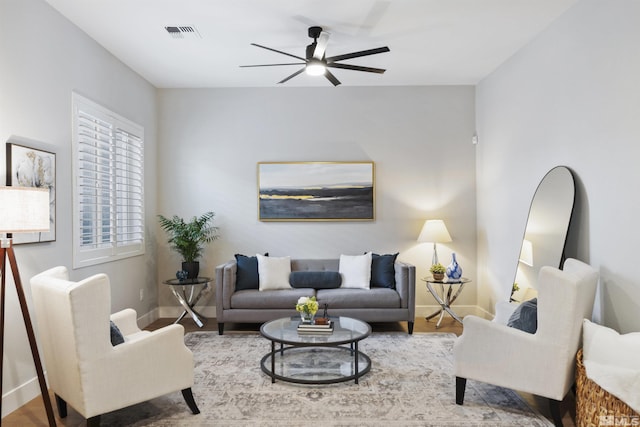 living room with ceiling fan, wood finished floors, visible vents, and baseboards