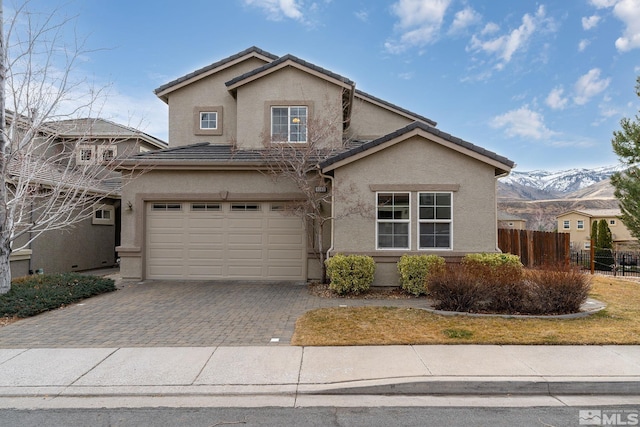 traditional-style house with decorative driveway, fence, a tiled roof, and stucco siding