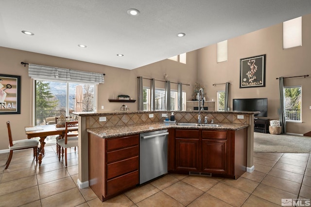 kitchen featuring a center island with sink, tasteful backsplash, open floor plan, a sink, and dishwasher