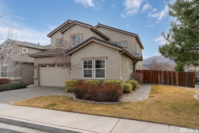 traditional-style house featuring a garage, stucco siding, fence, decorative driveway, and a front yard