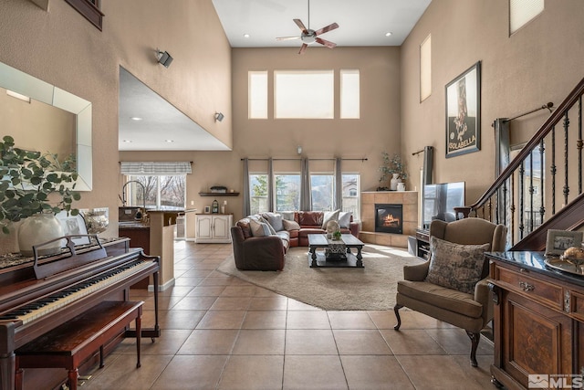 tiled living area featuring stairway, plenty of natural light, a fireplace, and a ceiling fan