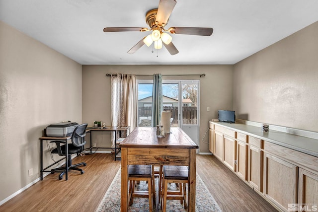 dining area with wood finished floors, a ceiling fan, and baseboards