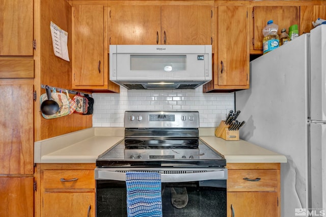 kitchen with light countertops, white appliances, brown cabinets, and decorative backsplash