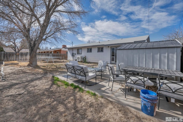 rear view of house with an outbuilding, outdoor lounge area, a storage shed, a patio area, and fence