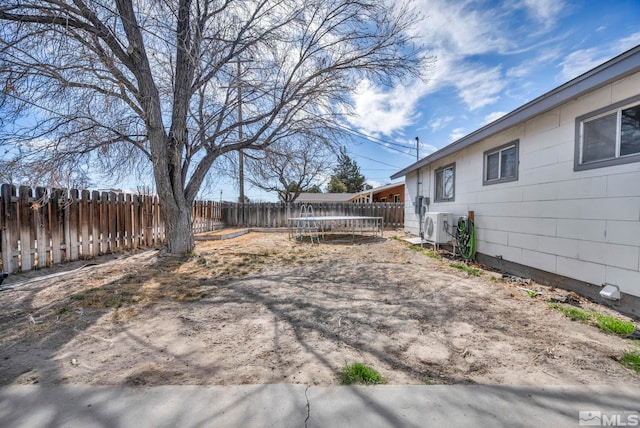 view of yard with ac unit, a fenced backyard, and a trampoline