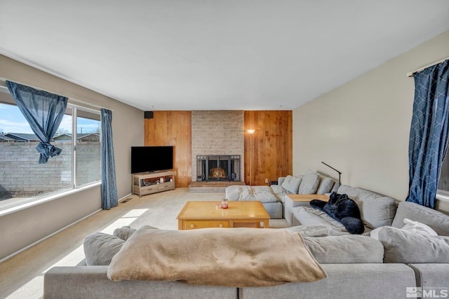 living area featuring a brick fireplace, light carpet, and wooden walls