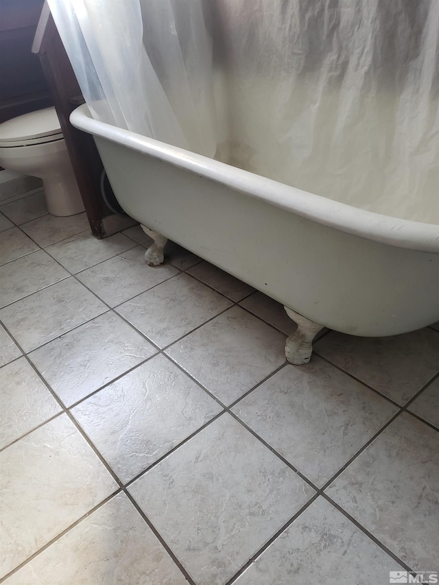 full bathroom with a tub, toilet, and tile patterned flooring