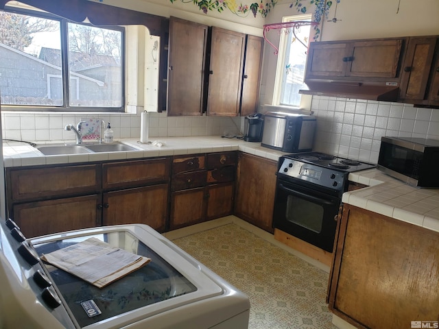 kitchen featuring tasteful backsplash, stainless steel microwave, under cabinet range hood, black / electric stove, and a sink