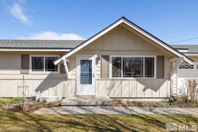 property entrance featuring a shingled roof and a yard