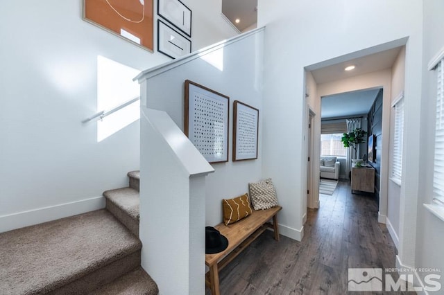 staircase with wood finished floors, a towering ceiling, and baseboards