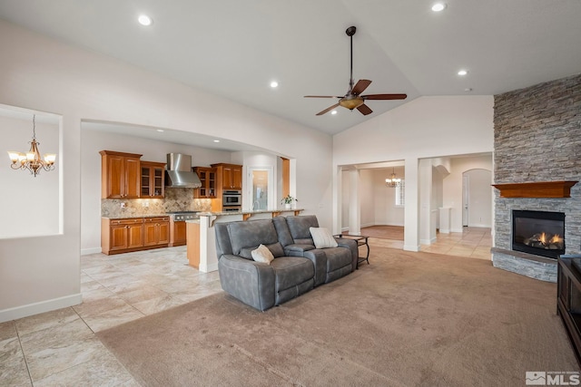 living room featuring arched walkways, a fireplace, light colored carpet, high vaulted ceiling, and ceiling fan with notable chandelier