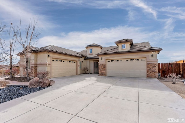 view of front of property featuring an attached garage, fence, driveway, stone siding, and stucco siding