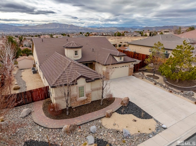 view of front of property featuring a mountain view, a garage, fence, stone siding, and stucco siding