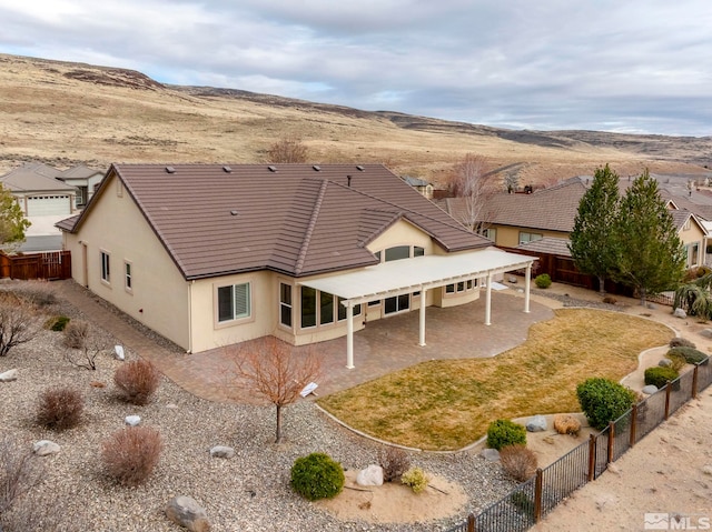 back of property with a mountain view, fence, a patio, and stucco siding