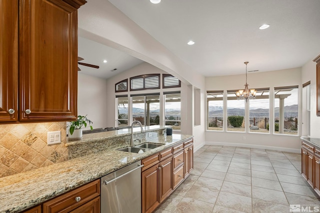 kitchen with brown cabinets, backsplash, stainless steel dishwasher, a sink, and a mountain view