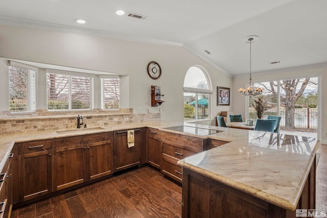 kitchen featuring light stone counters, black electric cooktop, a peninsula, a sink, and paneled dishwasher