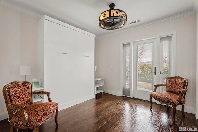 living area featuring baseboards, visible vents, hardwood / wood-style floors, and ornamental molding