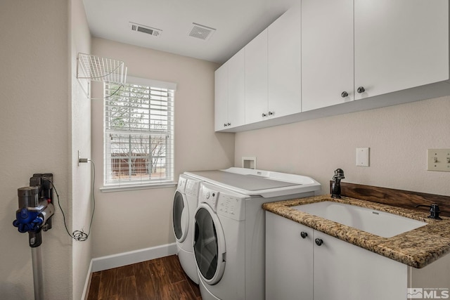 washroom with washing machine and clothes dryer, a sink, visible vents, cabinet space, and dark wood finished floors