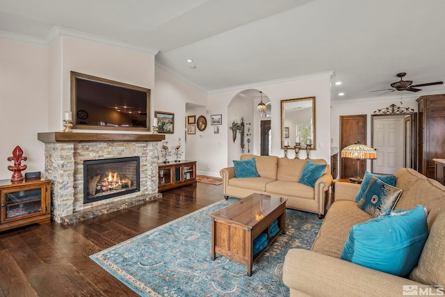 living area featuring arched walkways, lofted ceiling, a fireplace, wood finished floors, and ornamental molding