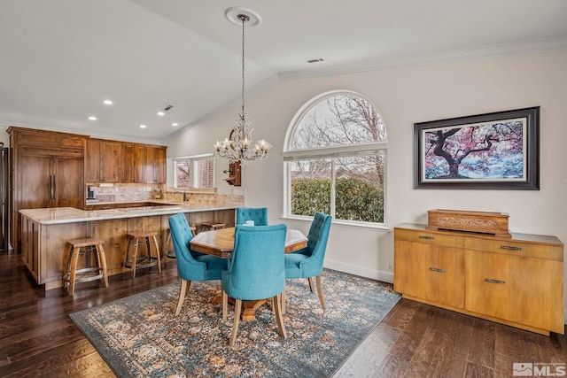 dining space featuring lofted ceiling, a notable chandelier, crown molding, and dark wood-type flooring