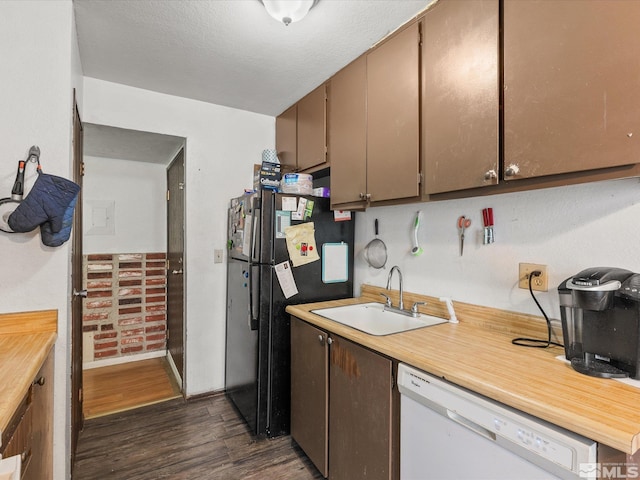 kitchen featuring white dishwasher, dark wood-type flooring, a sink, light countertops, and freestanding refrigerator