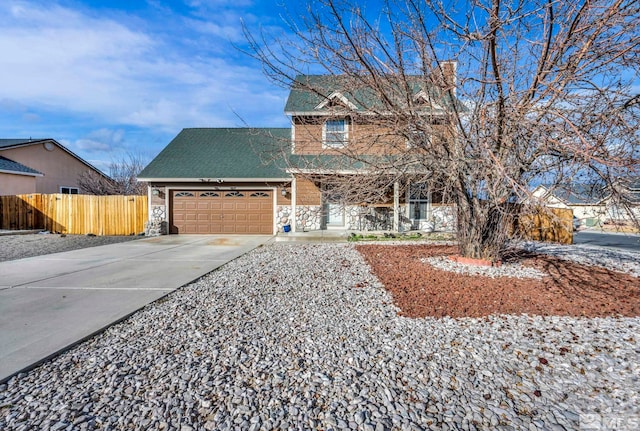 traditional-style house featuring a garage, stone siding, fence, and concrete driveway