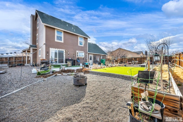 rear view of property with a patio, a fenced backyard, a fire pit, a lawn, and a vegetable garden