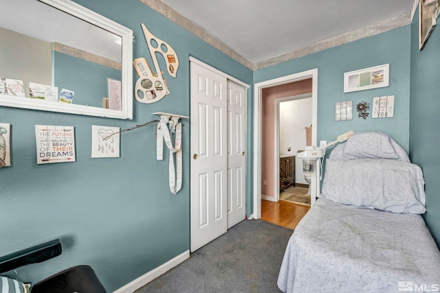 bedroom featuring baseboards, dark carpet, and a closet