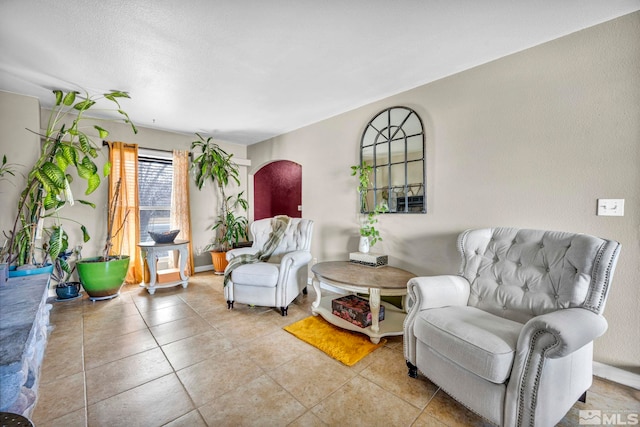 sitting room featuring arched walkways and light tile patterned floors