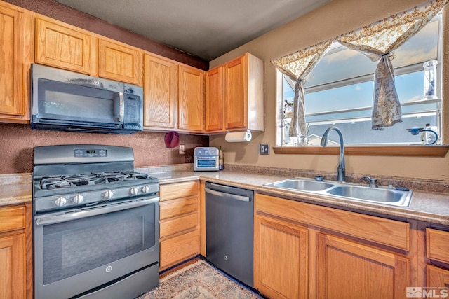 kitchen featuring appliances with stainless steel finishes, light countertops, and a sink