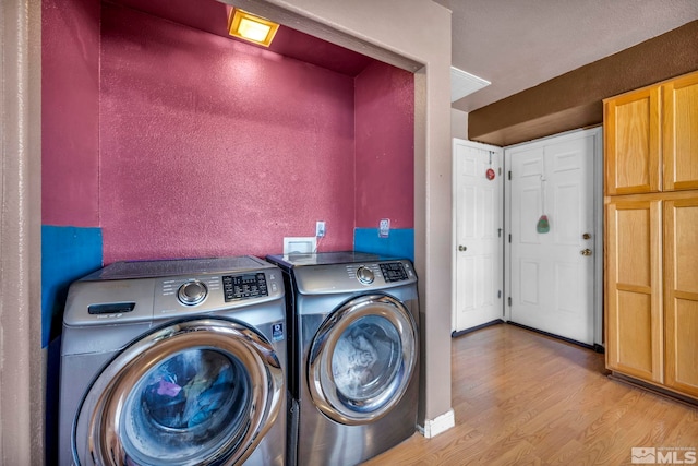 washroom with a textured wall, laundry area, washing machine and dryer, and light wood-style floors