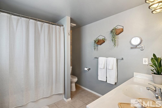 bathroom featuring toilet, tile patterned flooring, baseboards, and a sink