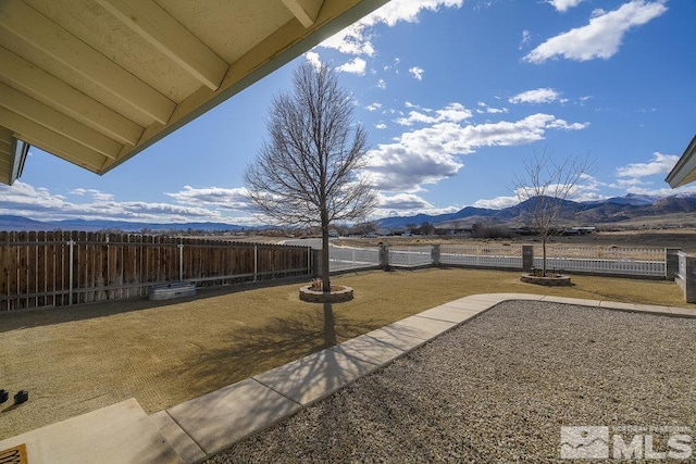 view of yard with a fenced backyard, a mountain view, and a patio