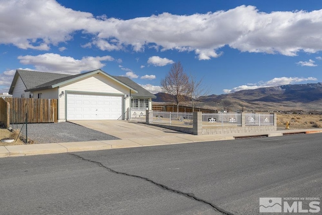 ranch-style house featuring driveway, an attached garage, fence, and a mountain view