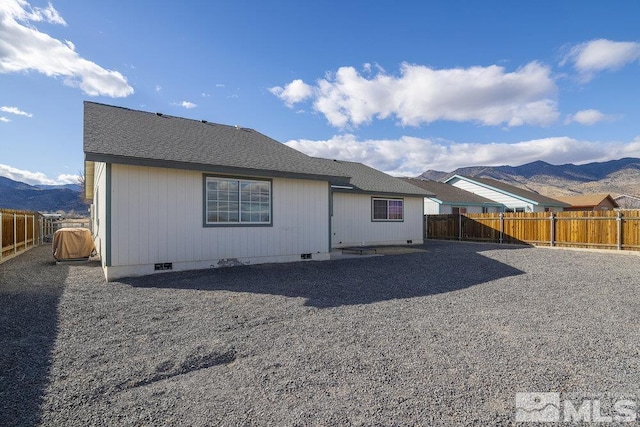 rear view of property with roof with shingles, crawl space, a fenced backyard, and a mountain view